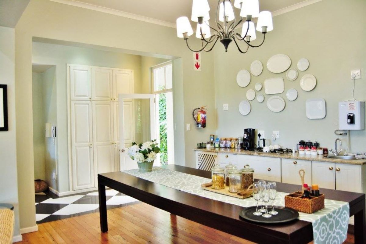 A well-maintained kitchen area featuring hardwood and checkered tile flooring, built-in cabinetry with stone countertops, and an elegant central chandelier.