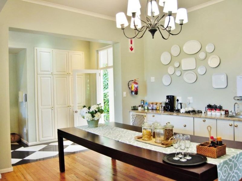 A well-maintained kitchen area featuring hardwood and checkered tile flooring, built-in cabinetry with stone countertops, and an elegant central chandelier.