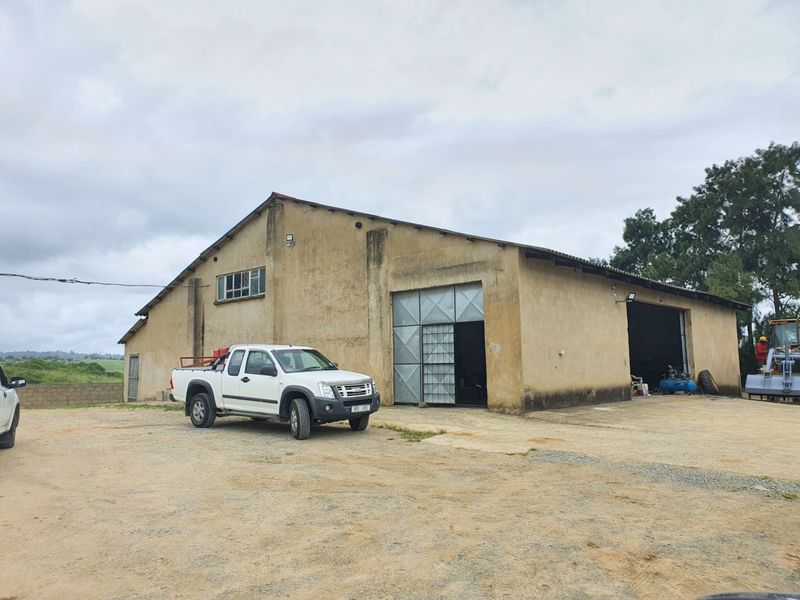 Industrial warehouse building featuring a large concrete apron and sliding metal access doors, showing signs of exterior weathering and wear.