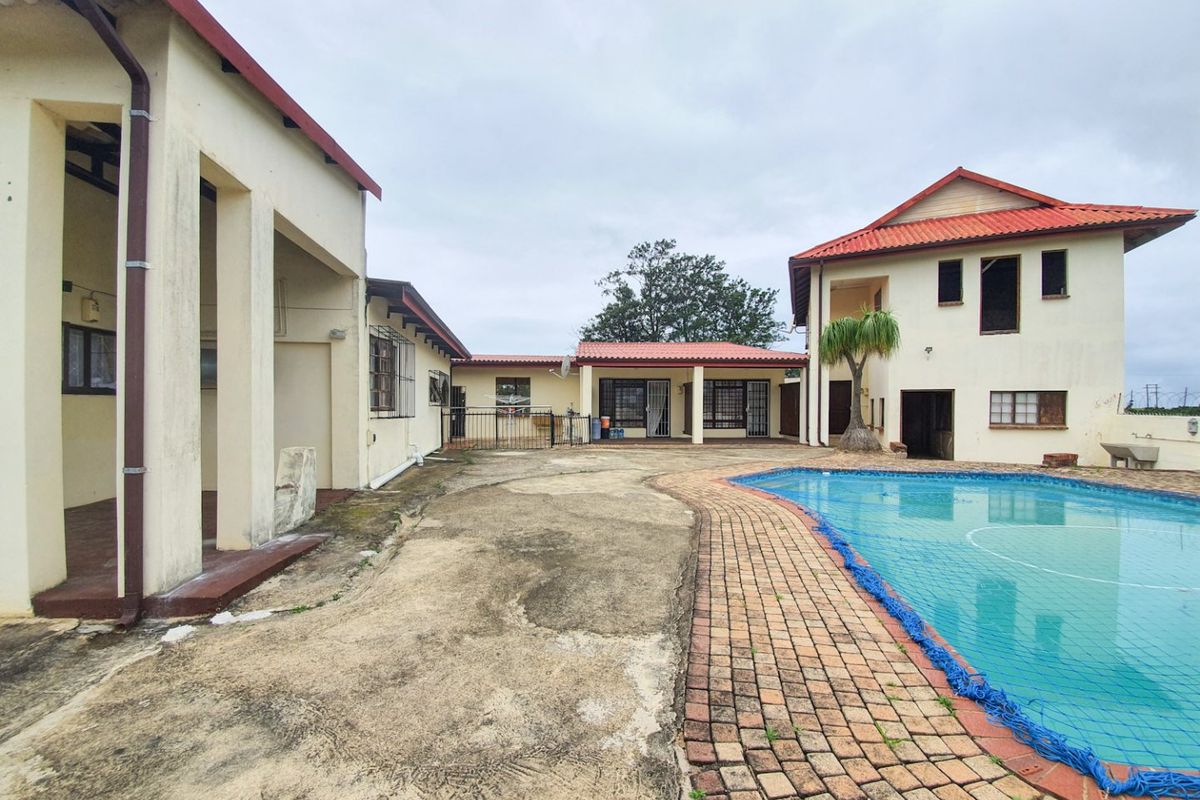 Exterior view of the pool area featuring a swimming pool, brick paving, and multiple building structures with tiled roofs.