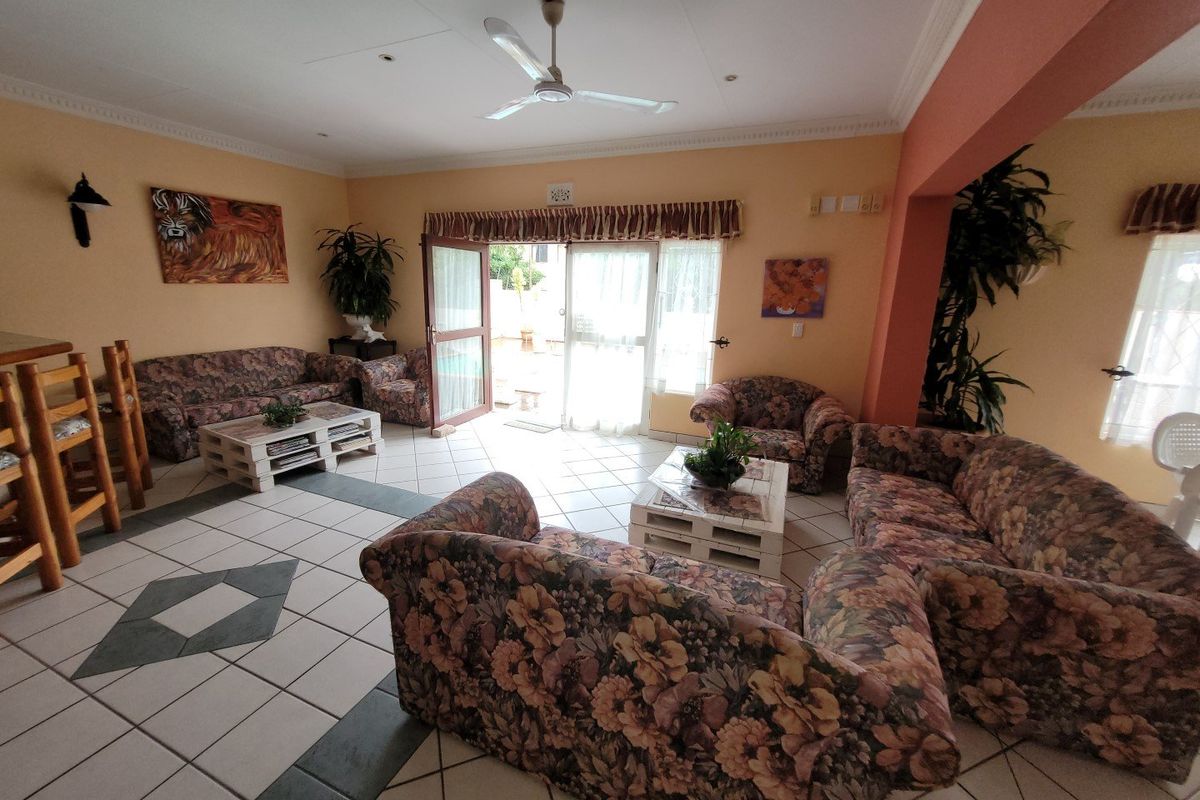 Spacious living area featuring tiled flooring, a ceiling fan, and direct access to the outdoor patio through double glass doors.