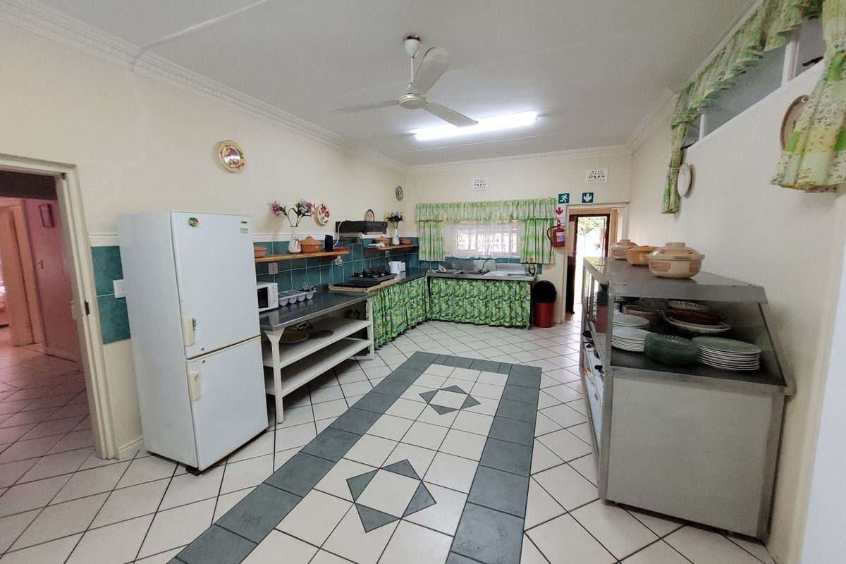 A functional commercial kitchen space featuring tiled flooring, stainless steel prep areas, and basic built-in cabinetry, suitable for renovation or modernization.