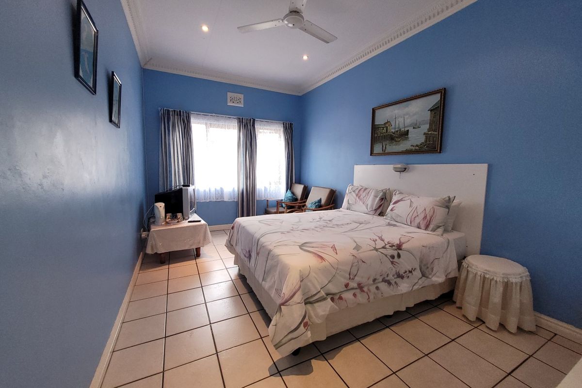 A bedroom featuring tiled flooring, a ceiling fan, and decorative cornice detailing, providing a functional space with neutral finishes.
