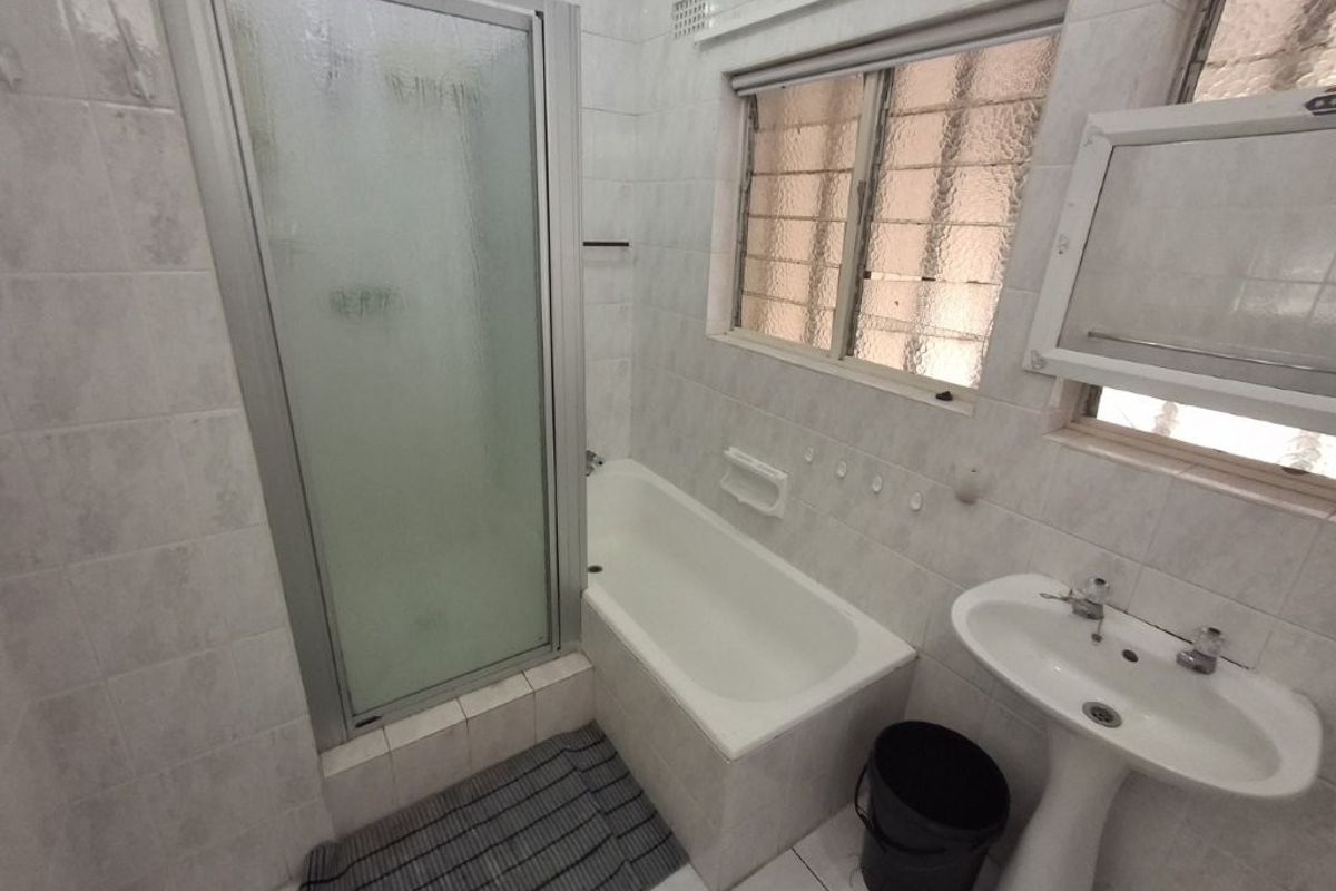 A dated bathroom featuring a shower enclosure, bathtub, and pedestal basin with tiled finishes, offering potential for modernization and renovation.