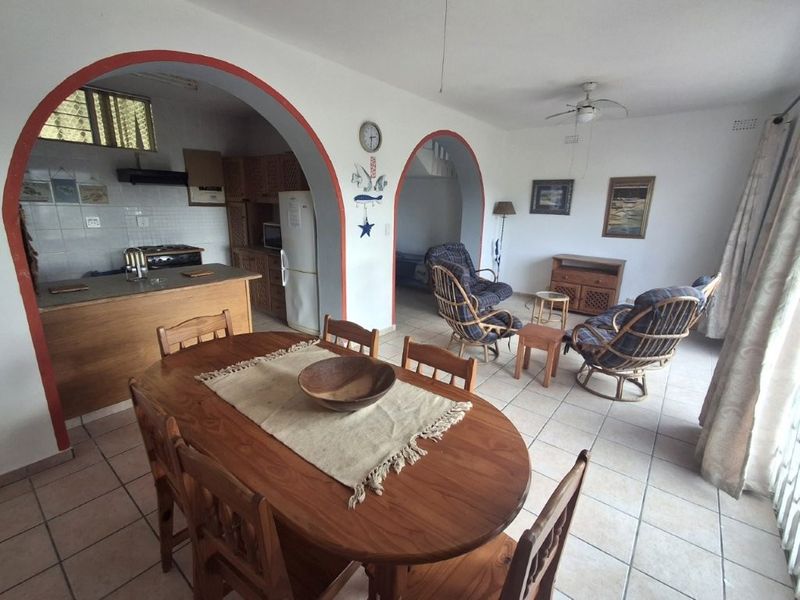 Open-plan living and dining area featuring arched architectural details, tiled flooring, and an adjoining kitchen space with built-in cabinetry.