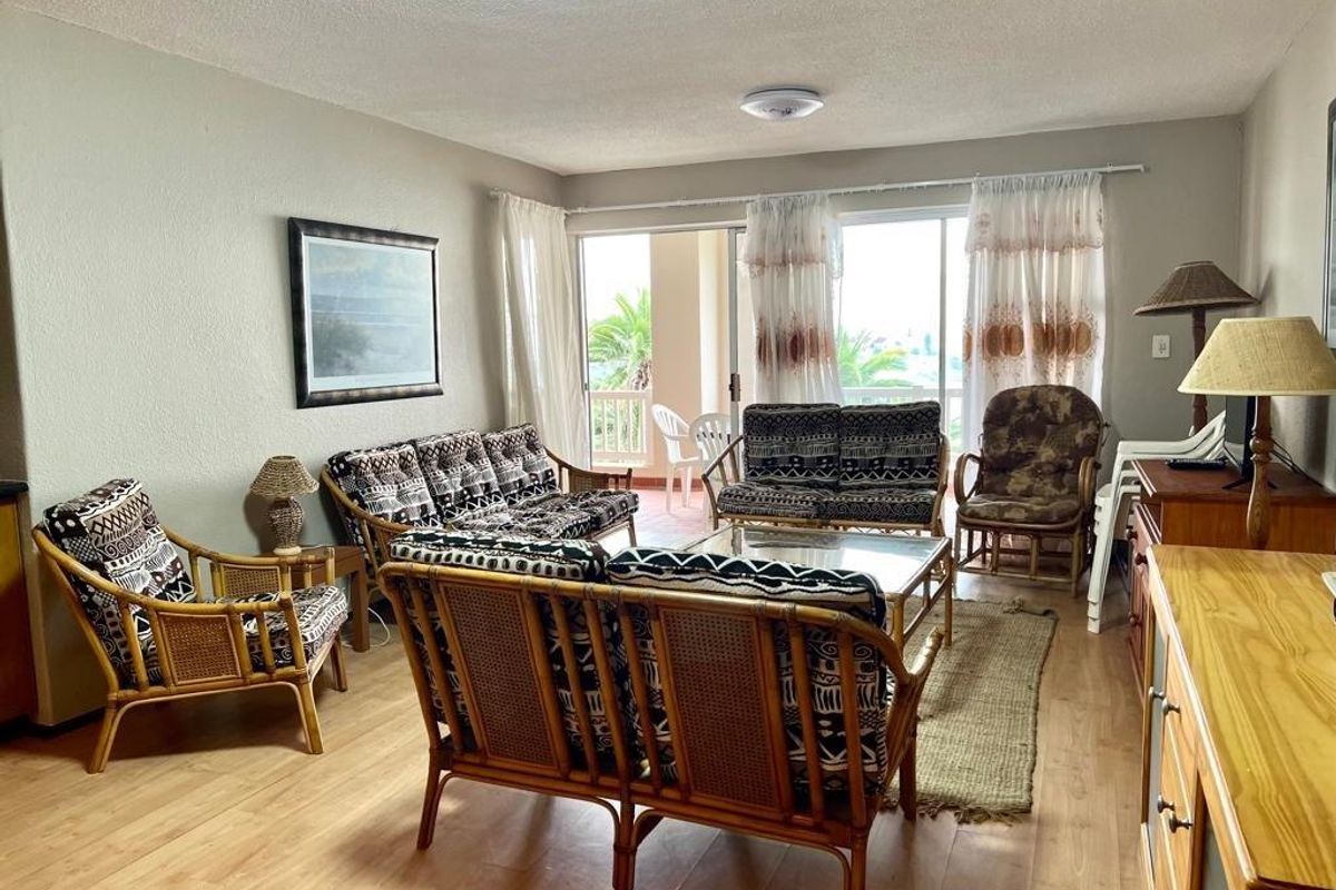 Spacious living room featuring laminate flooring and large sliding glass doors that provide access to an outdoor balcony area.