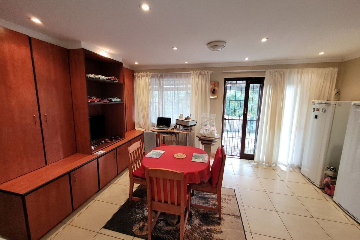A living area featuring tiled flooring, recessed lighting, and extensive built-in cabinetry, with direct access to the exterior through a security-fitted sliding door.