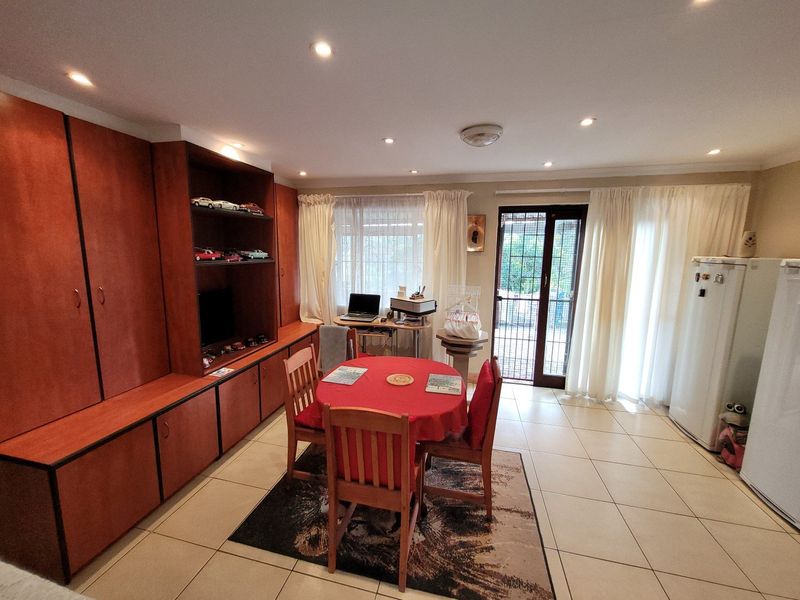 A living area featuring tiled flooring, recessed lighting, and extensive built-in cabinetry, with direct access to the exterior through a security-fitted sliding door.
