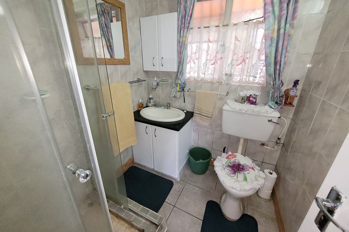A compact bathroom featuring a shower enclosure, vanity basin, and toilet, finished with full-height wall tiling and floor tiles.