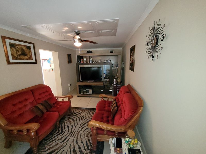 A living room featuring tiled flooring, a ceiling fan, and coved ceiling details, providing a functional space for relaxation.