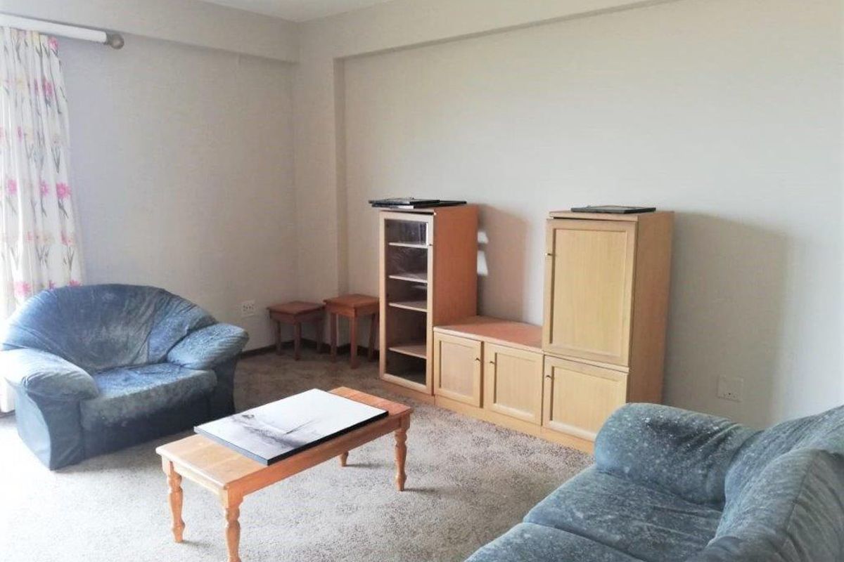 A neutrally painted living room featuring carpeted flooring and a curtain rail, offering a blank canvas for personalization.