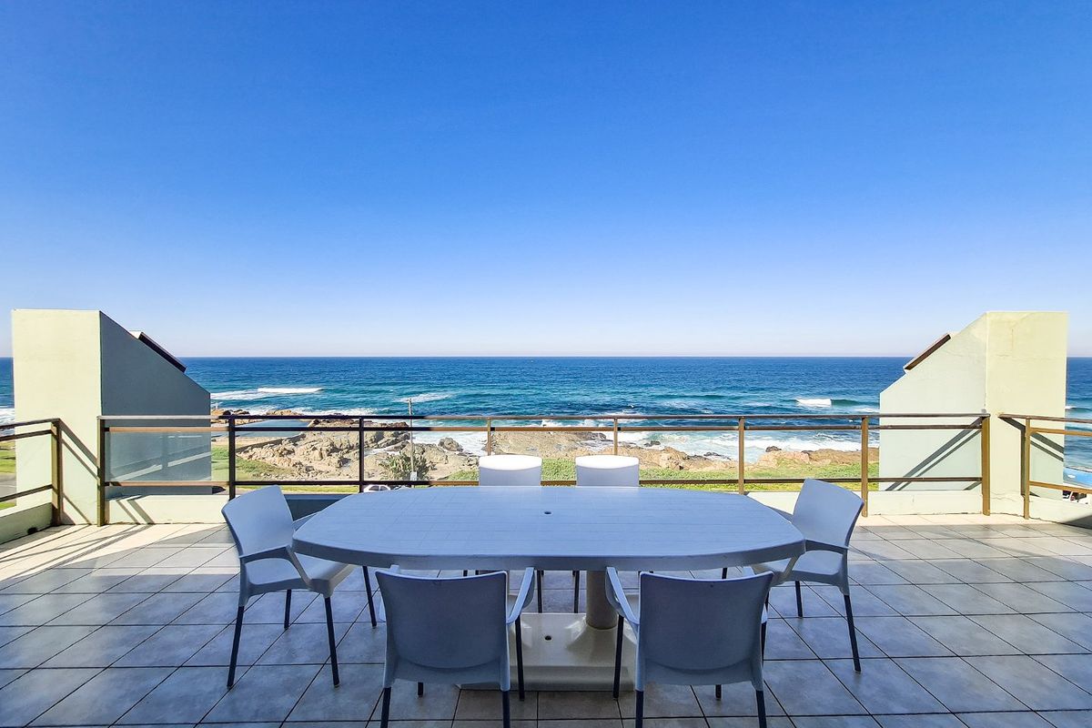 Spacious outdoor balcony featuring tiled flooring and metal railings, offering expansive, unobstructed views of the ocean and coastline.