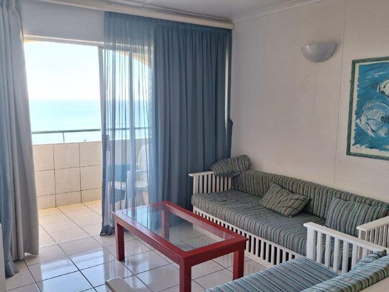 Living room featuring tiled flooring and large sliding glass doors opening onto a balcony with ocean views.