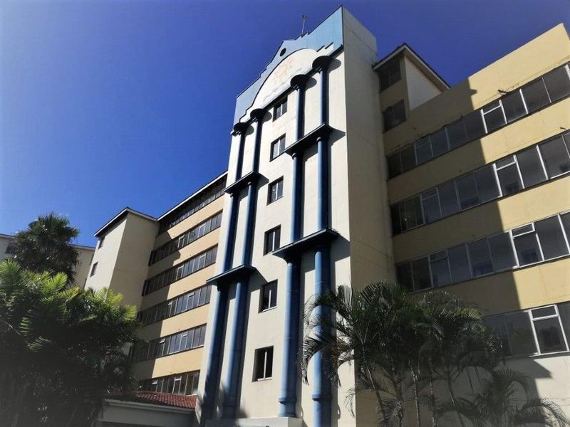 Exterior view of a multi-story apartment building featuring a prominent central architectural facade with blue decorative columns.