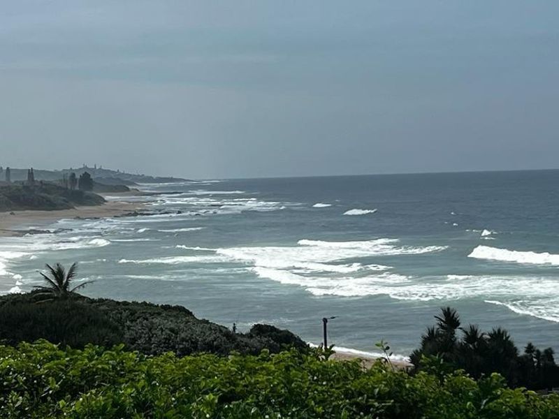 A scenic coastal view overlooking the ocean, sandy beach, and natural vegetation, highlighting the property's prime location.