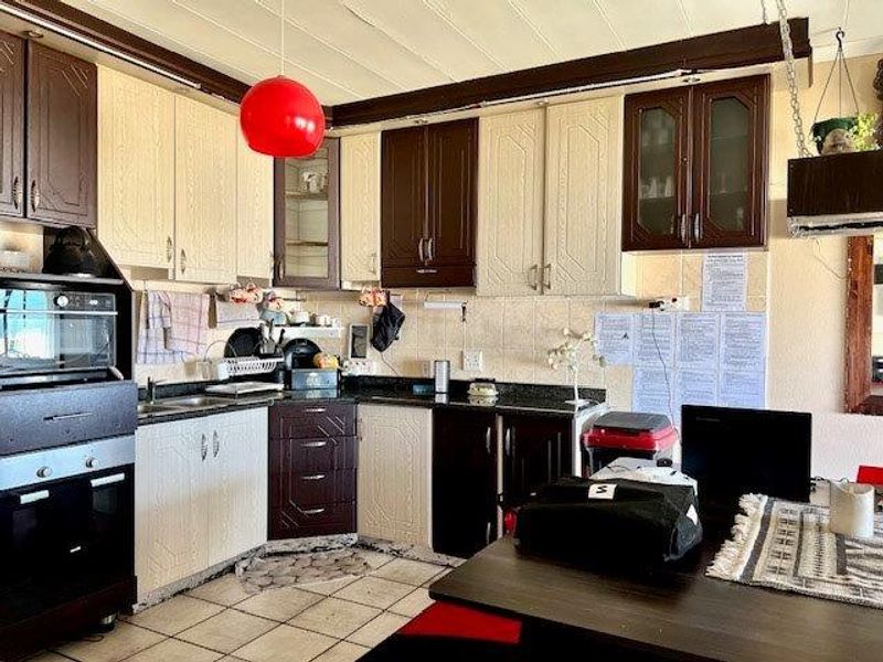 A functional kitchen featuring two-tone cabinetry, granite countertops, tiled backsplash, and built-in oven, offering a practical layout with ample storage space.