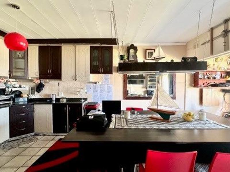 Open-plan kitchen and dining area featuring two-tone built-in cabinetry, tiled flooring, and a large central dining space.