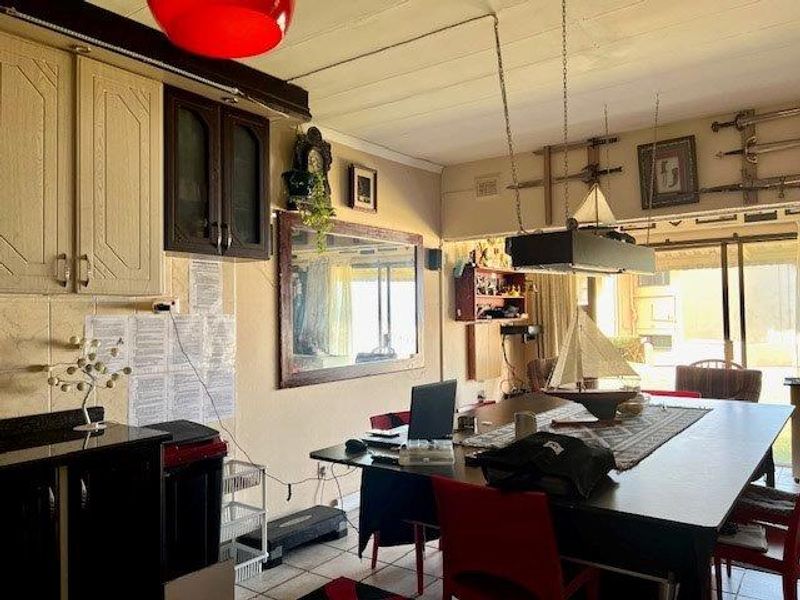 Open plan living and kitchen area featuring tiled flooring, dated cabinetry, and sliding glass doors leading to an outdoor space.