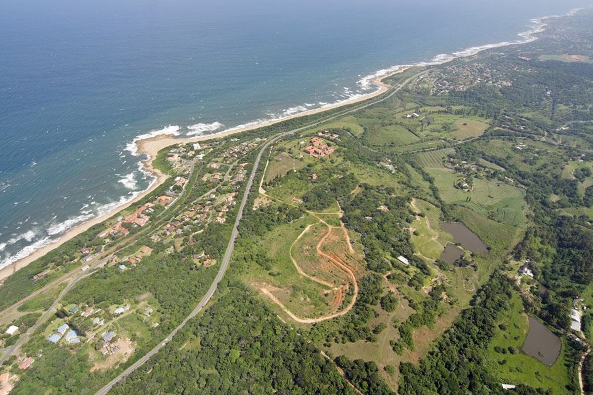 An expansive aerial view of the coastal farm property, showcasing the surrounding landscape, natural vegetation, and proximity to the coastline.