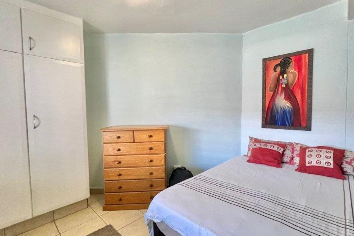 A bedroom featuring tiled flooring and a built-in wardrobe, providing functional storage space within the apartment.