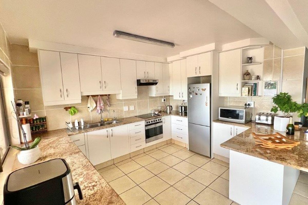 Functional kitchen featuring granite countertops, tiled backsplash, built-in cabinetry, and integrated oven with hob, offering a practical layout for daily cooking.