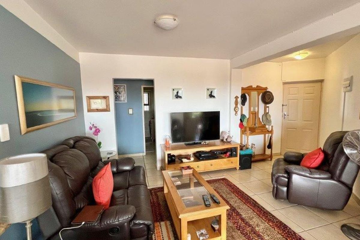 A living room featuring tiled flooring, neutral wall finishes, and a functional layout with access to adjacent rooms.