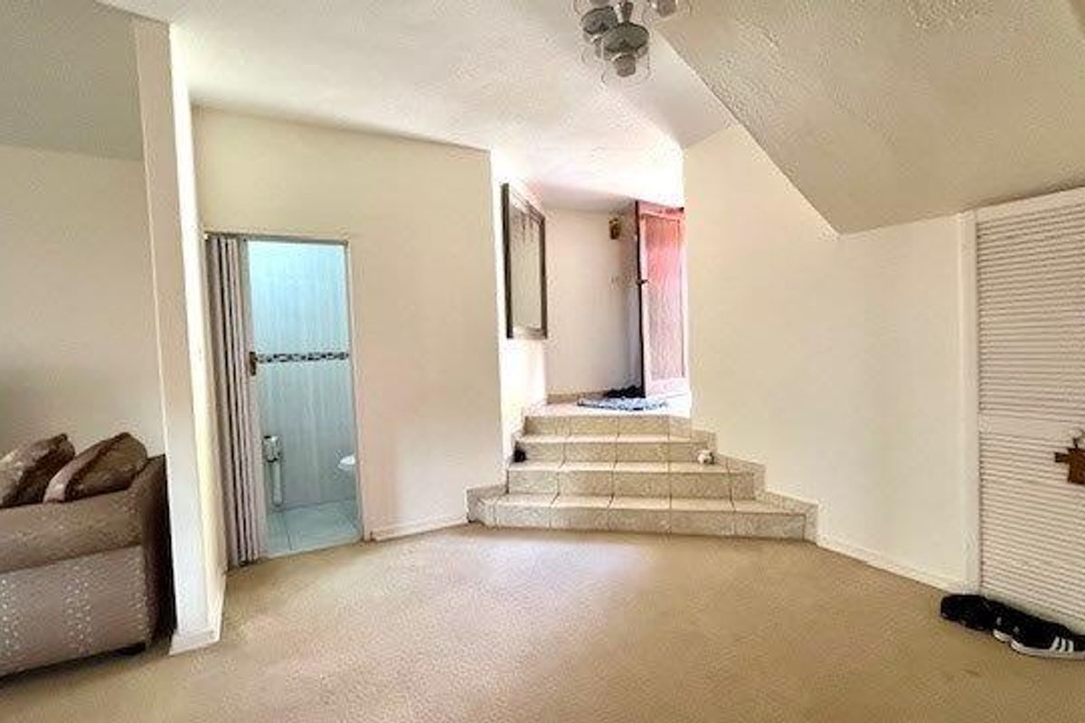 A living area featuring a tiled staircase leading to an upper level, with louvered closet doors and access to an adjacent bathroom.