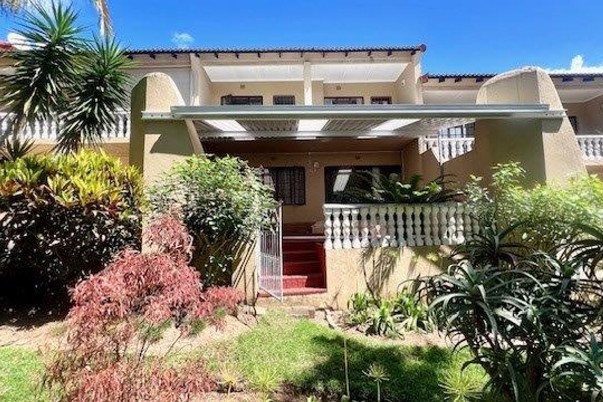 Rear view of the townhouse featuring a covered patio area, balustrade detailing, and access stairs leading to the garden.