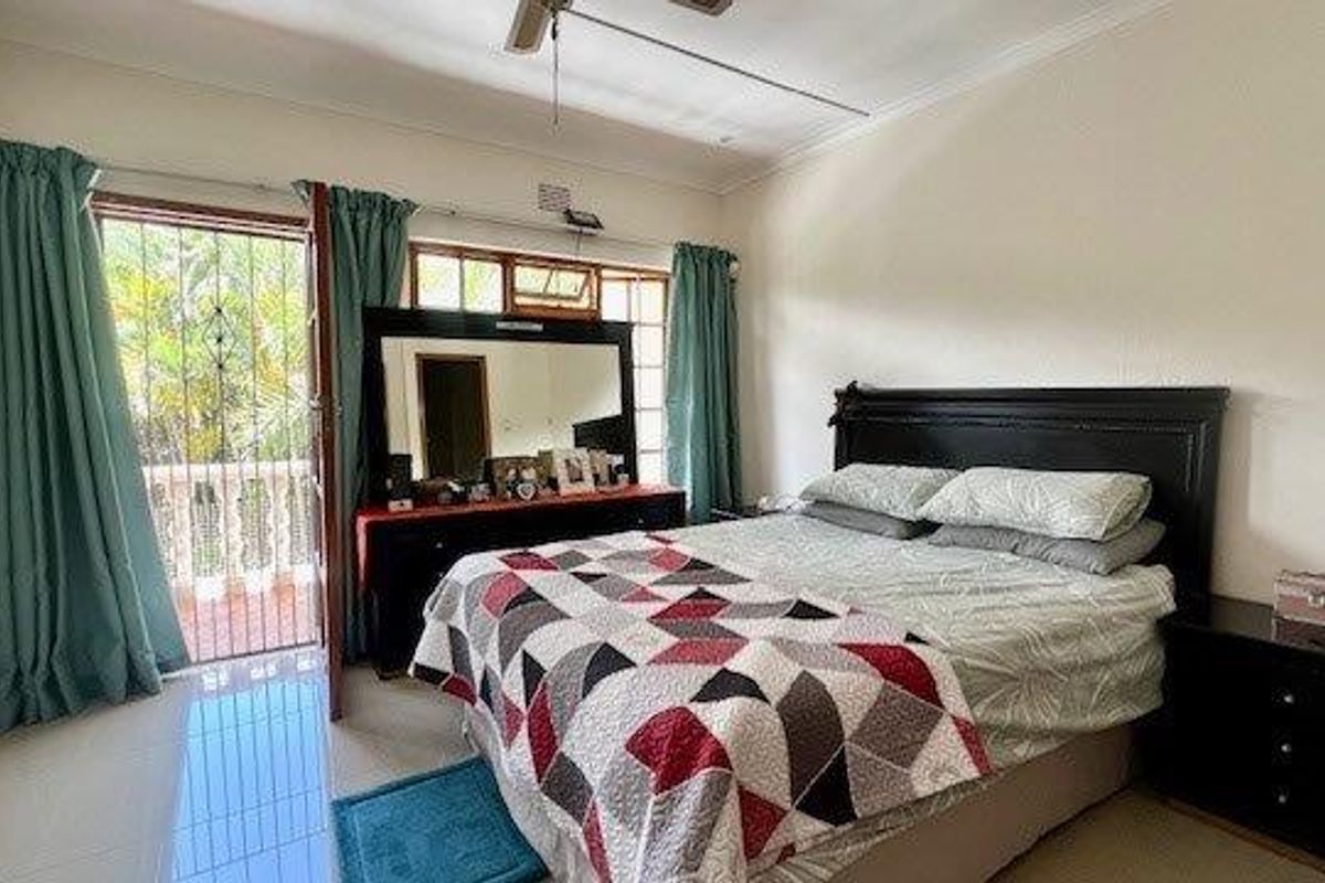 A bedroom featuring tiled flooring, built-in cupboards, a ceiling fan, and direct access to an outdoor balcony through a security gate.