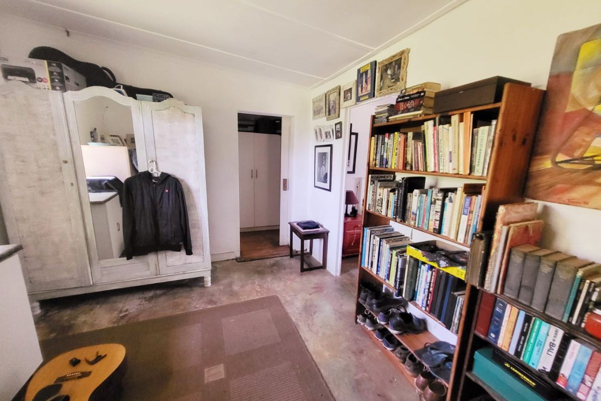 A bedroom featuring concrete flooring and built-in cupboard storage, offering a functional space with potential for cosmetic updates.