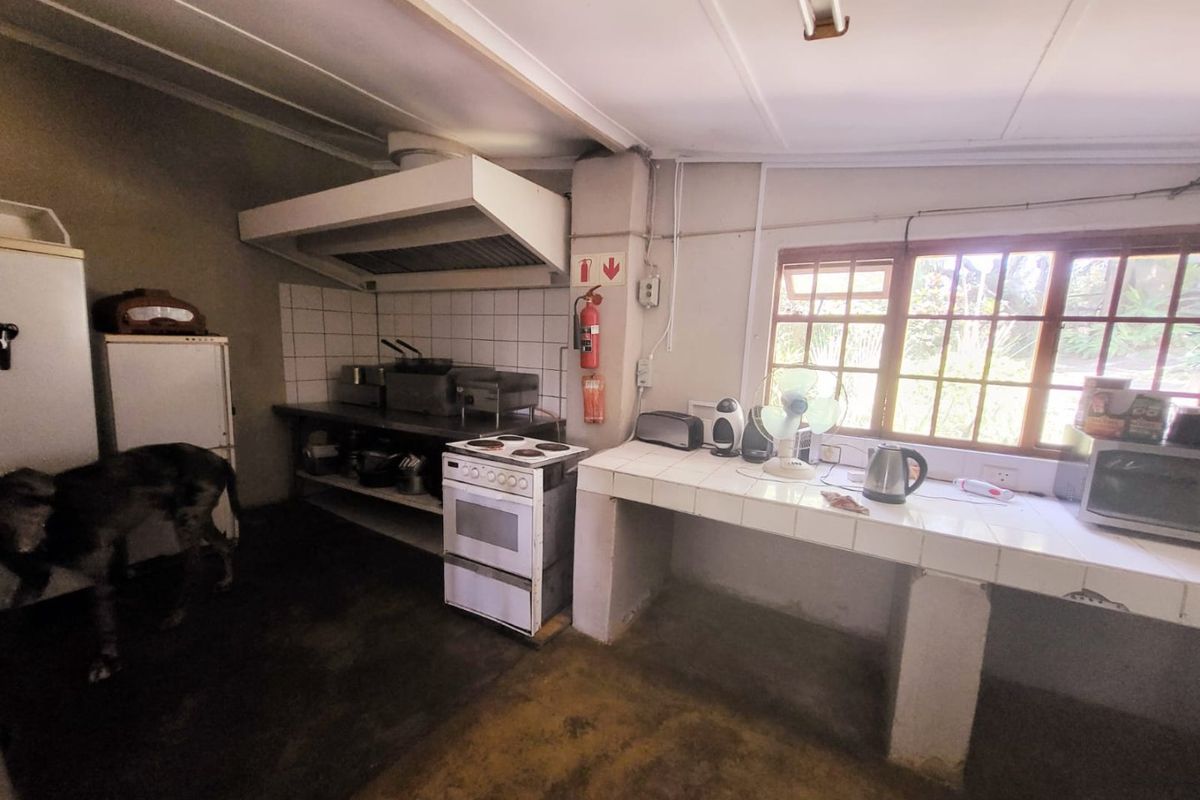 A functional farm-style kitchen featuring masonry base cabinetry, tiled countertops, a built-in extractor fan, and a freestanding stove.