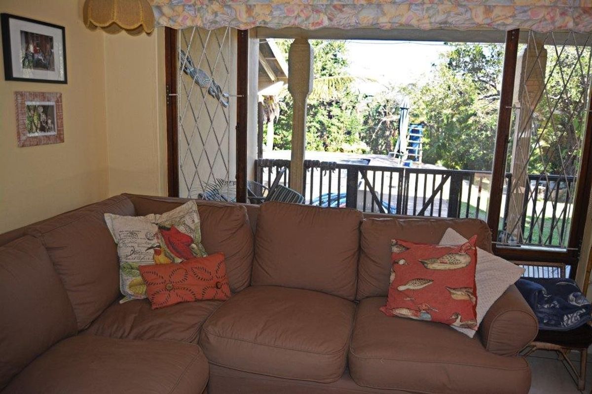 A living room area featuring large windows with security lattice, offering a view of the outdoor space and garden.