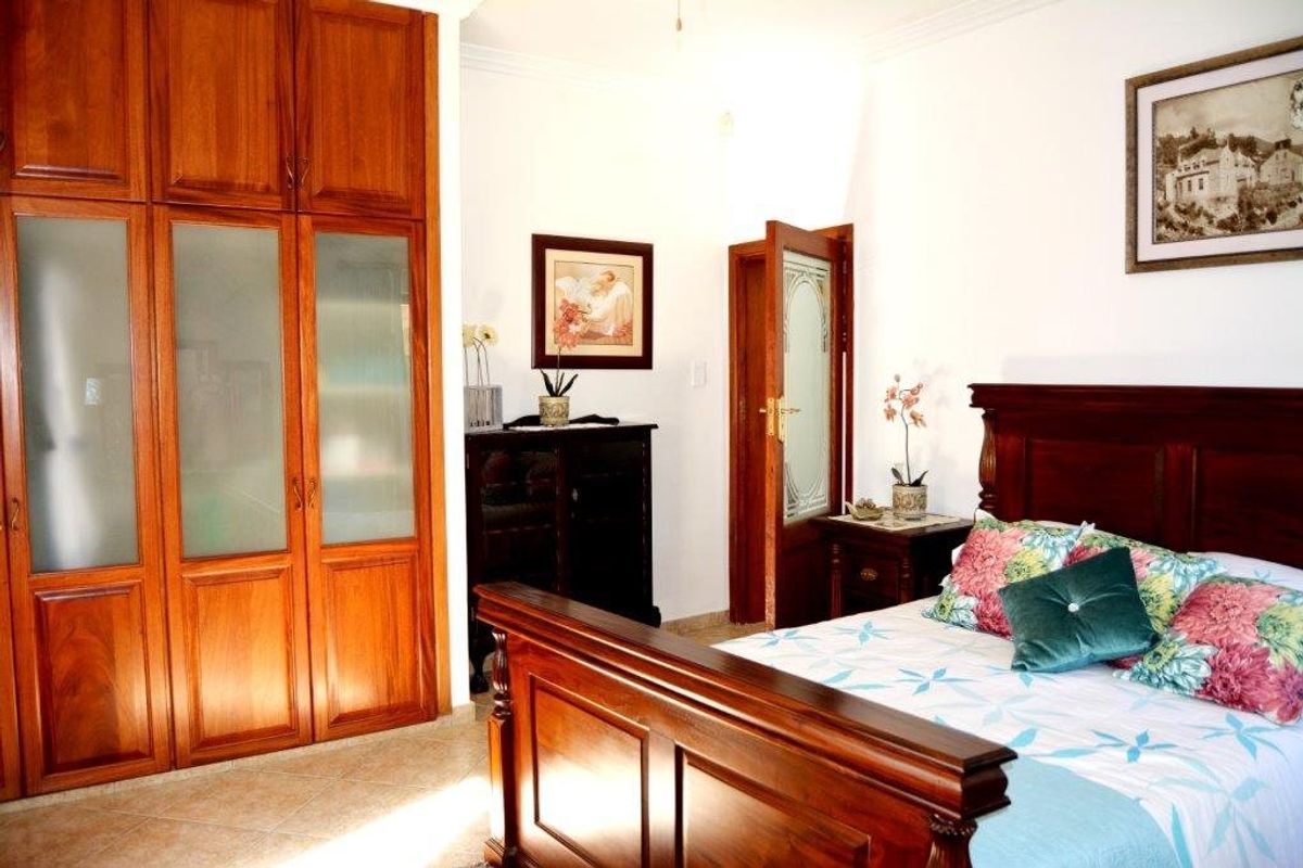 A well-maintained bedroom featuring built-in wooden cabinetry, tiled flooring, and classic crown molding details.