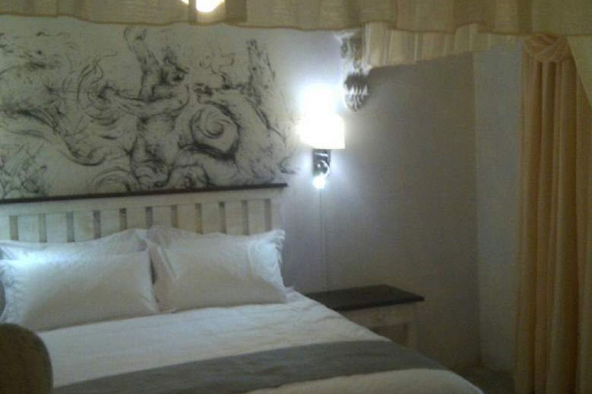 A bedroom featuring a bed with decorative wall art and integrated wall-mounted lighting.