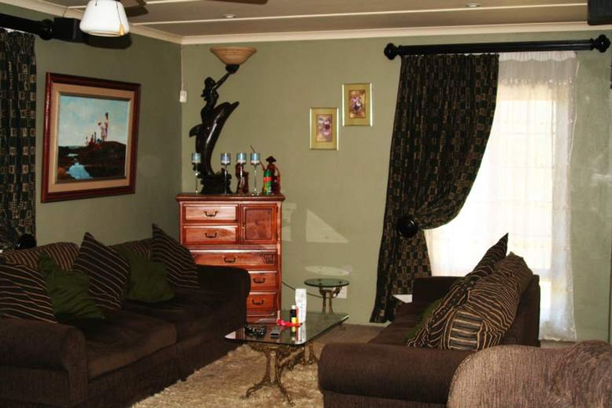 A living room area featuring olive green walls, recessed downlighting, and window treatments.