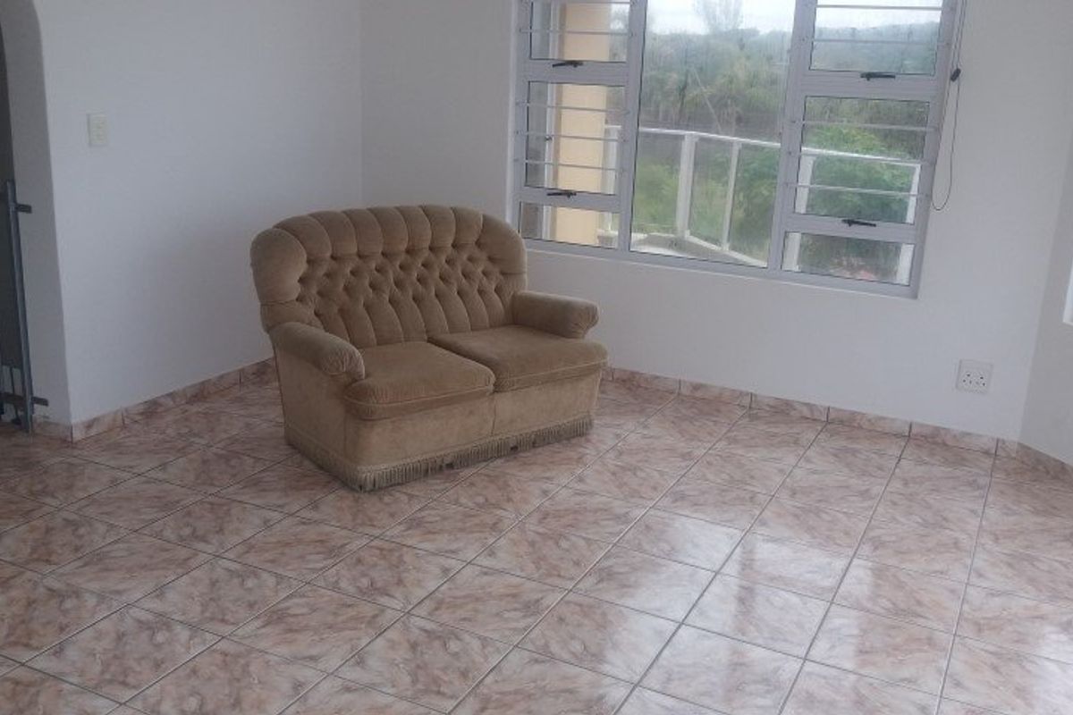 A living area featuring tiled flooring and large aluminium-framed windows with views, providing a bright and functional space.