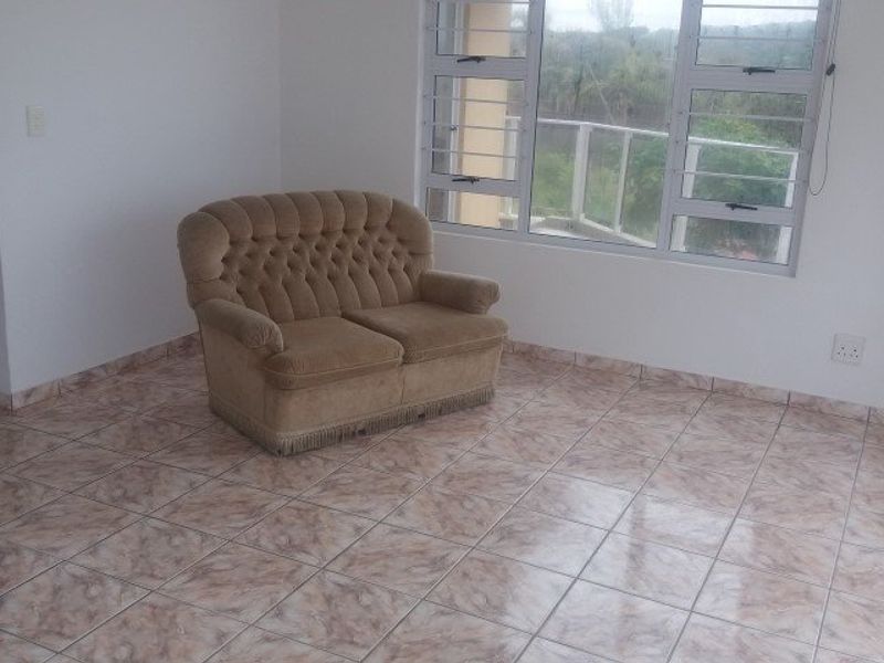A living area featuring tiled flooring and large aluminium-framed windows with views, providing a bright and functional space.