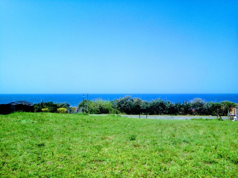A vacant residential plot featuring expansive ocean views and natural grassland terrain.