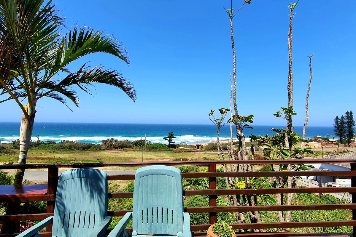 An elevated outdoor deck featuring a timber railing and expansive, unobstructed views of the coastline and ocean.