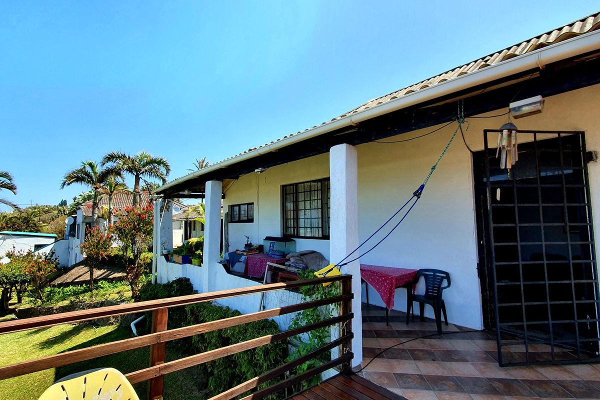 Covered patio area featuring tiled flooring, structural support pillars, and a timber railing overlooking the garden.
