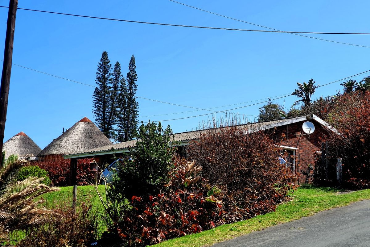 Exterior view of a commercial property featuring brick facade, thatched roof structures, and surrounding landscaped garden area.