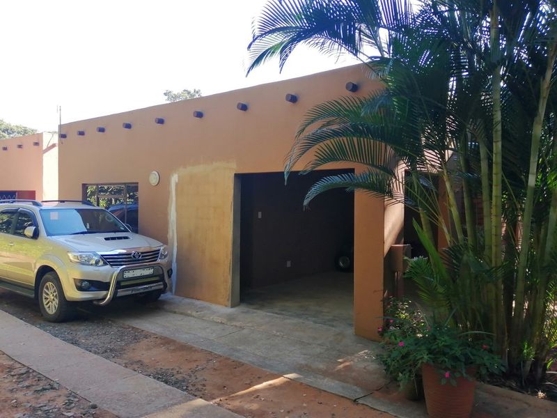 A single-car garage with an open entrance, featuring a stucco exterior finish and exposed rafter tails, showing signs of recent wall repairs.