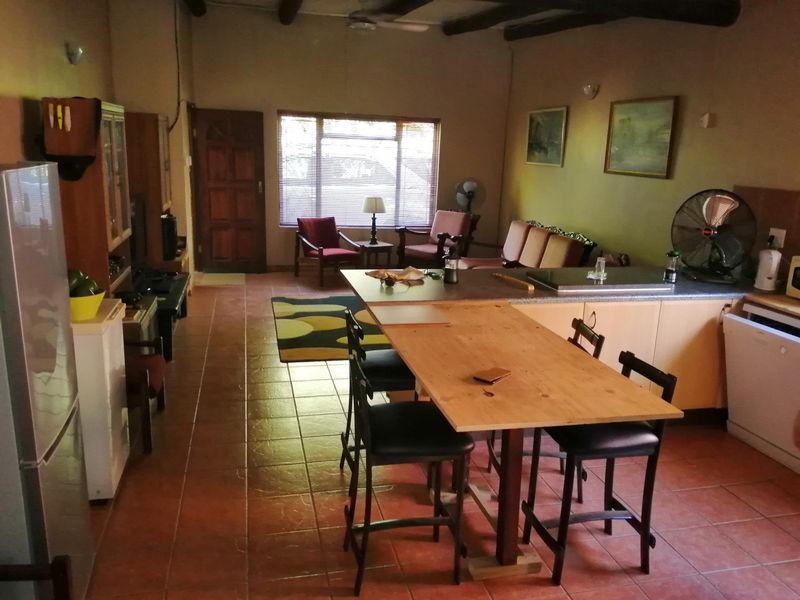 Open-plan living and kitchen area featuring tiled flooring, exposed timber ceiling beams, and a central kitchen island with built-in hob.