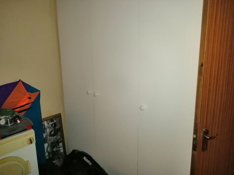 A bedroom interior featuring a white built-in wardrobe and a wooden door.