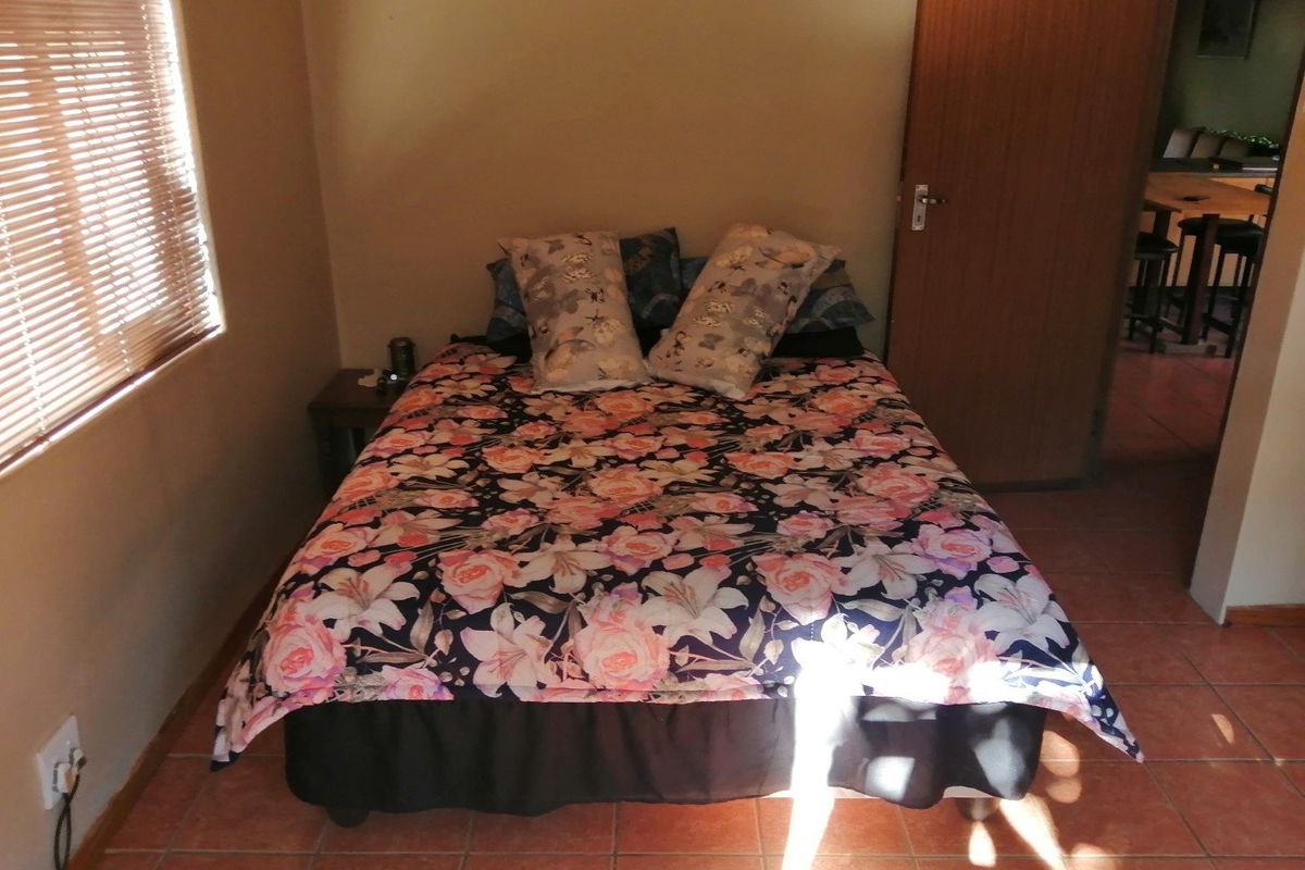 A functional bedroom featuring tiled flooring, a timber door, and venetian blinds, offering a simple and practical living space.