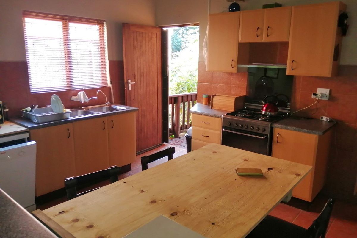 Functional kitchen featuring wooden cabinetry, gas stove, double sink, and direct access to an outdoor area, offering potential for modern cosmetic updates.