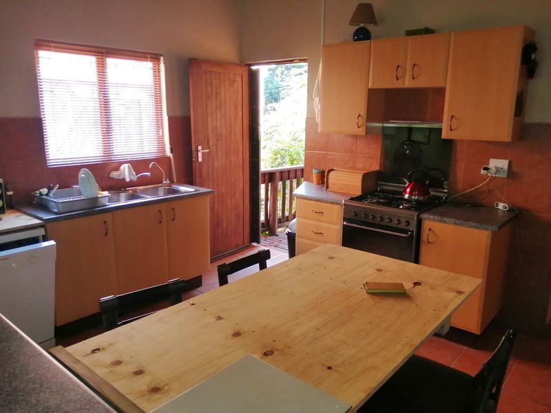 Functional kitchen featuring wooden cabinetry, gas stove, double sink, and direct access to an outdoor area, offering potential for modern cosmetic updates.