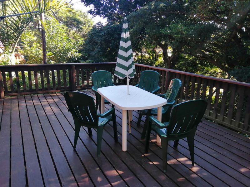 An elevated timber deck patio featuring a wooden balustrade and views of the surrounding trees.