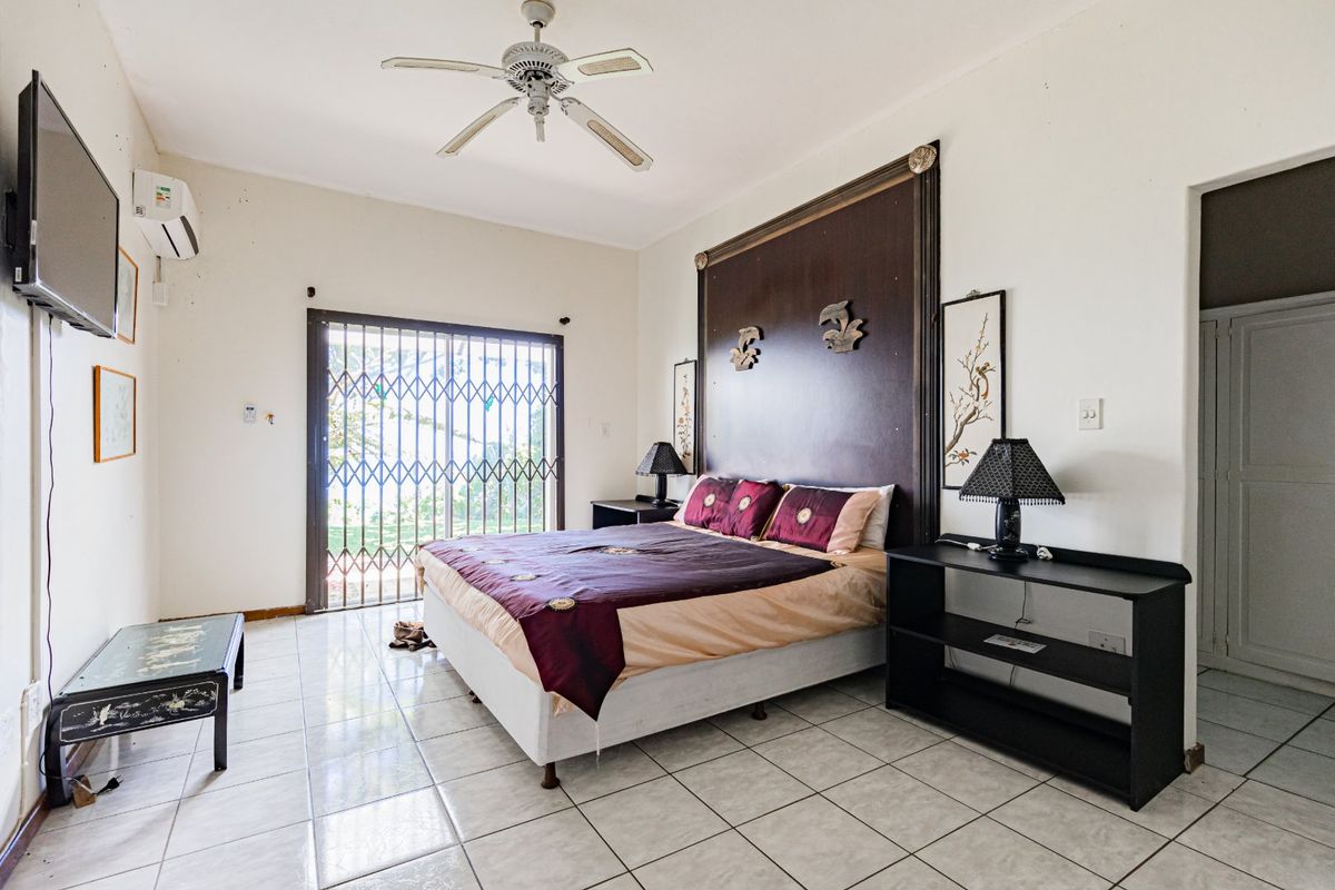 Spacious bedroom featuring tiled flooring, a ceiling fan, split-system air conditioning, and a secure sliding door with a metal security gate.