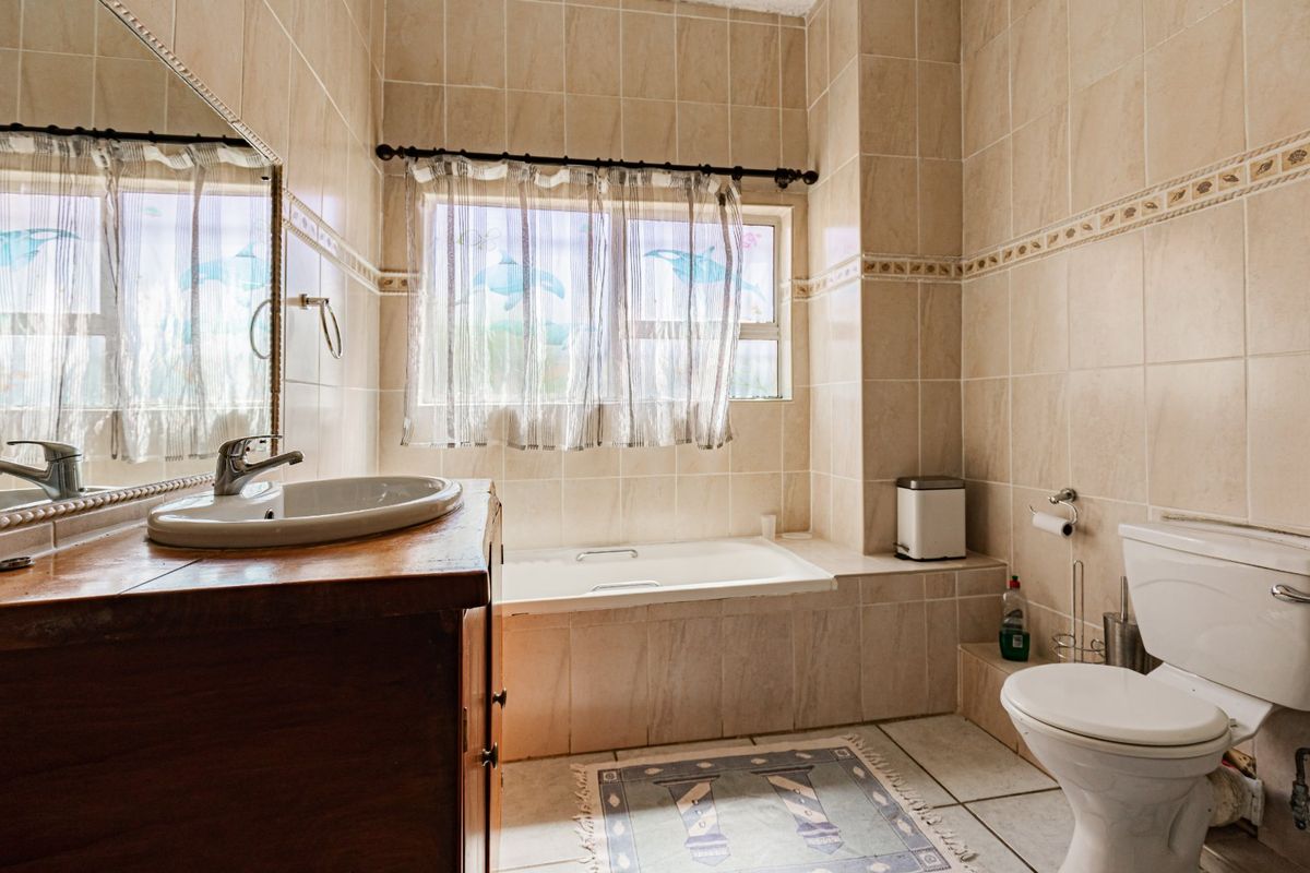 A functional bathroom featuring a built-in bathtub, tiled wall finishes, a vessel sink vanity, and a standard toilet.